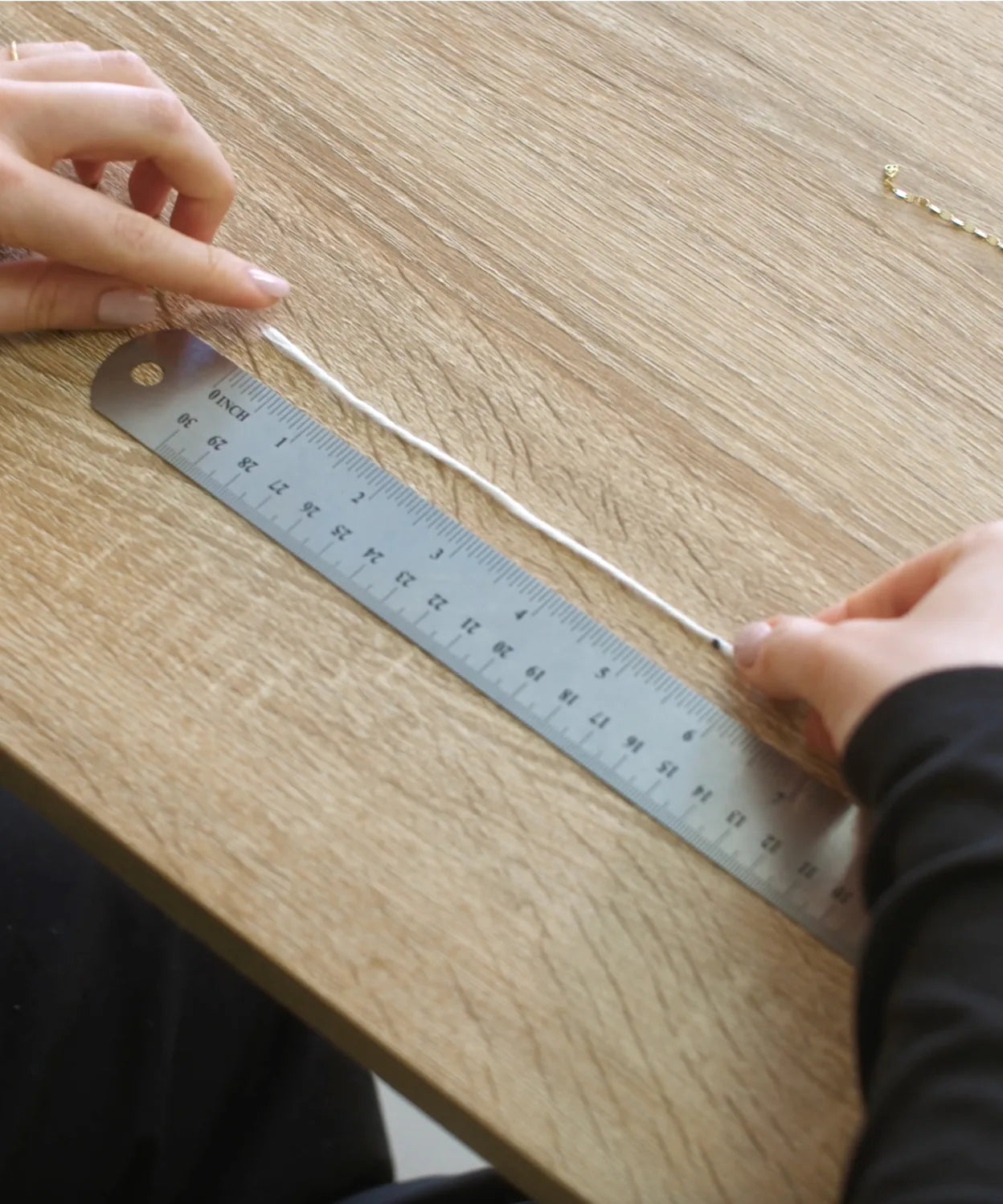 String placed next to a ruler, showing how to measure marked string length for bracelet sizing.