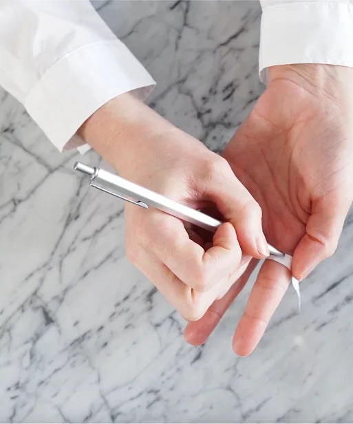 Pen marking the point where the paper strip meets, showing how to record finger measurement for ring sizing.