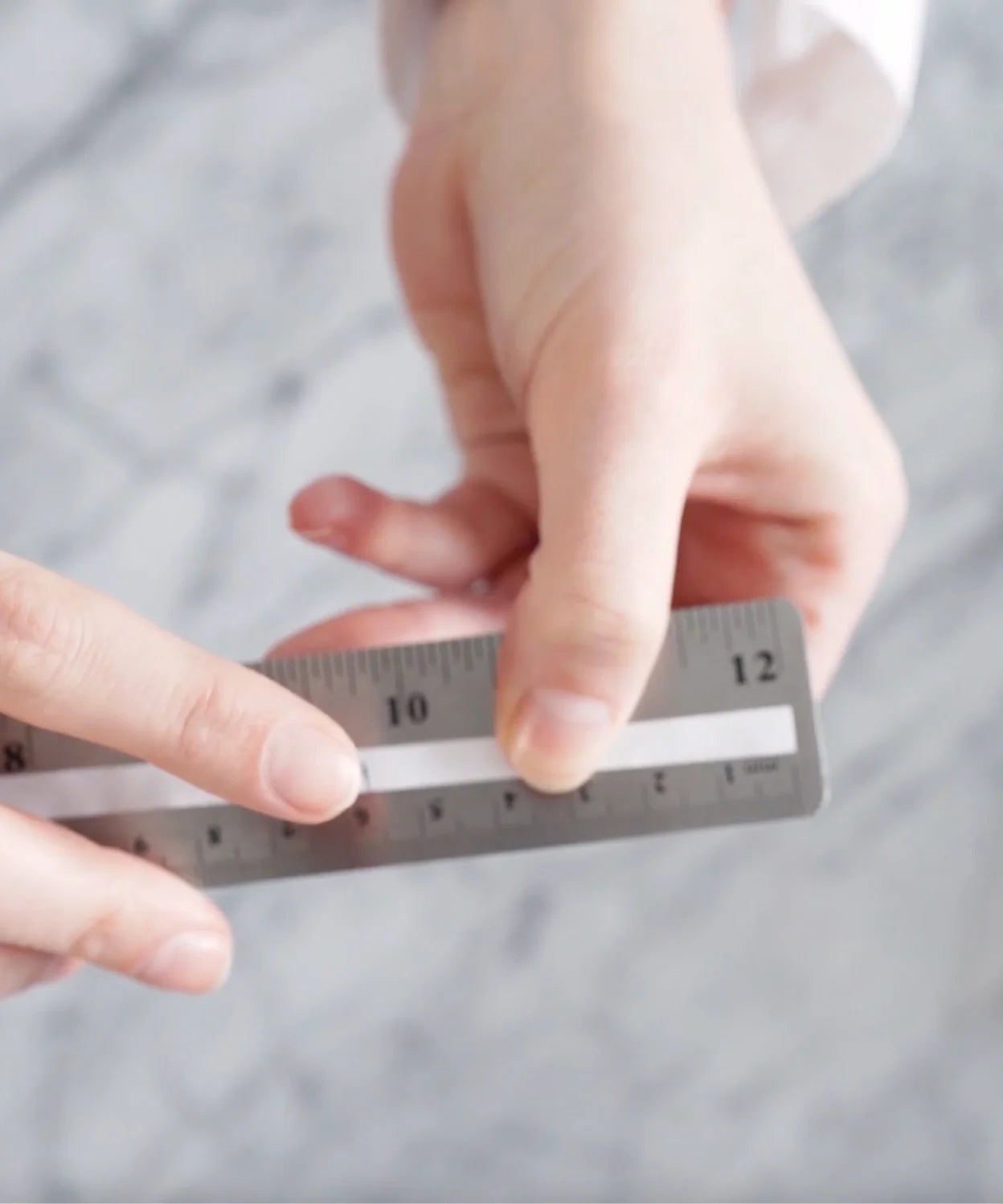 Paper strip placed against a ruler, showing how to measure finger circumference in millimeters for ring size.