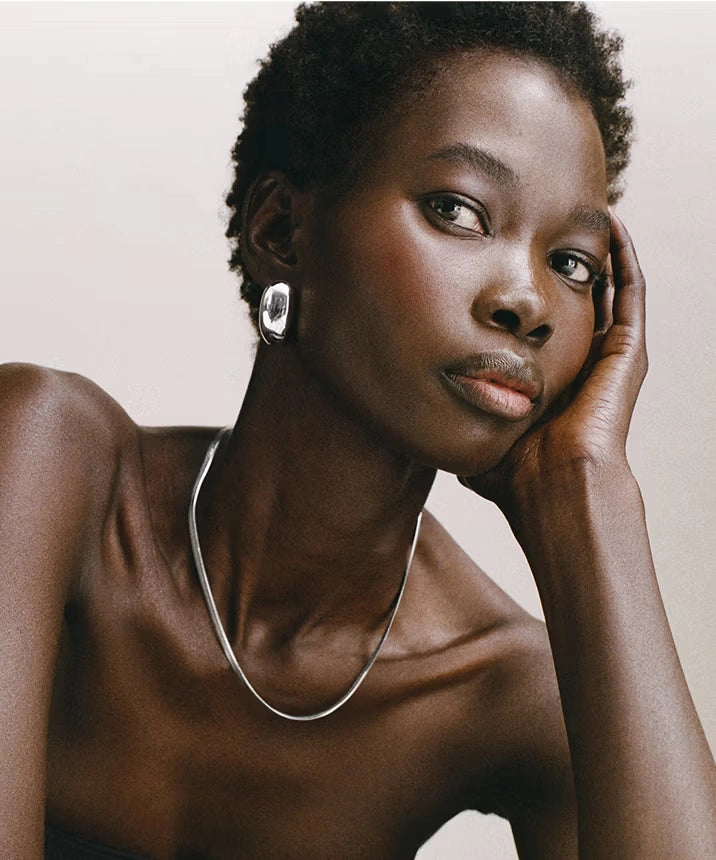 Elegant model wearing sterling silver necklace and matching earrings, showcasing minimalist fine jewelry design