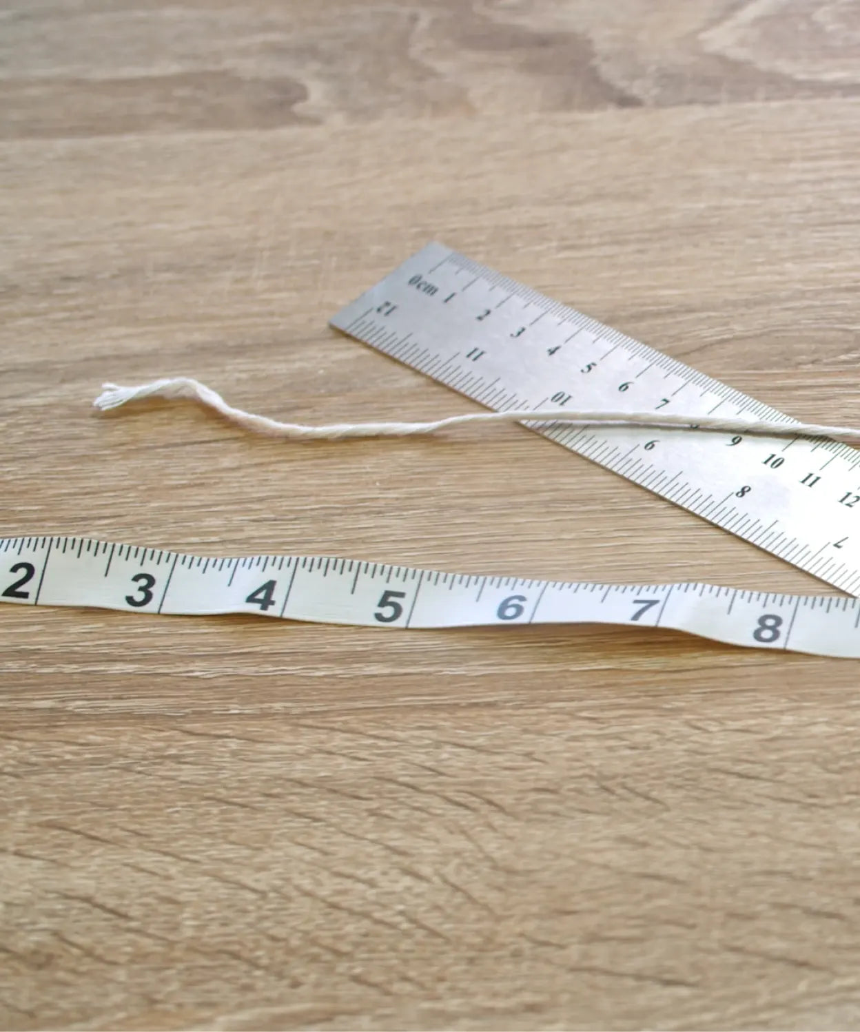 String, ruler, and measuring tape on a wooden table, showing tools for measuring wrist size in the LeMing bracelet size guide.