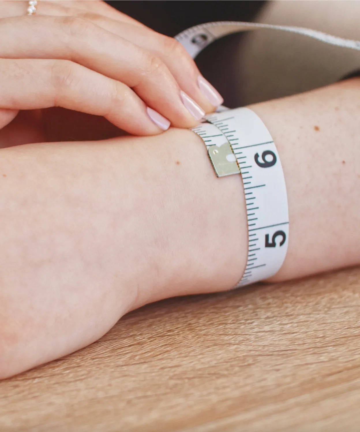 Close-up of measuring tape around a wrist, showing wrist measurement for choosing the right bracelet size.