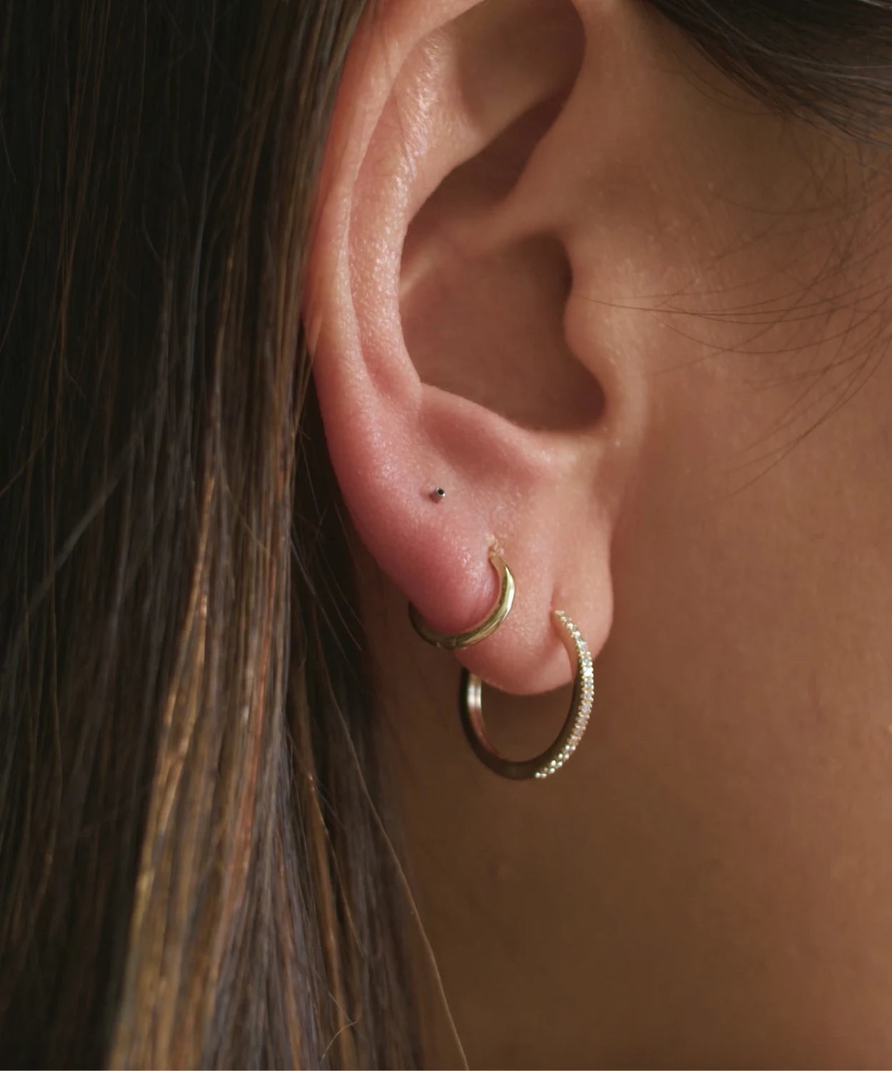 Step 2 showing the flat back stud post pushed through the piercing until visible from the front of the ear.