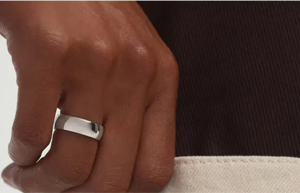 Close-up of hand wearing polished platinum band ring, showcasing modern fine jewelry design