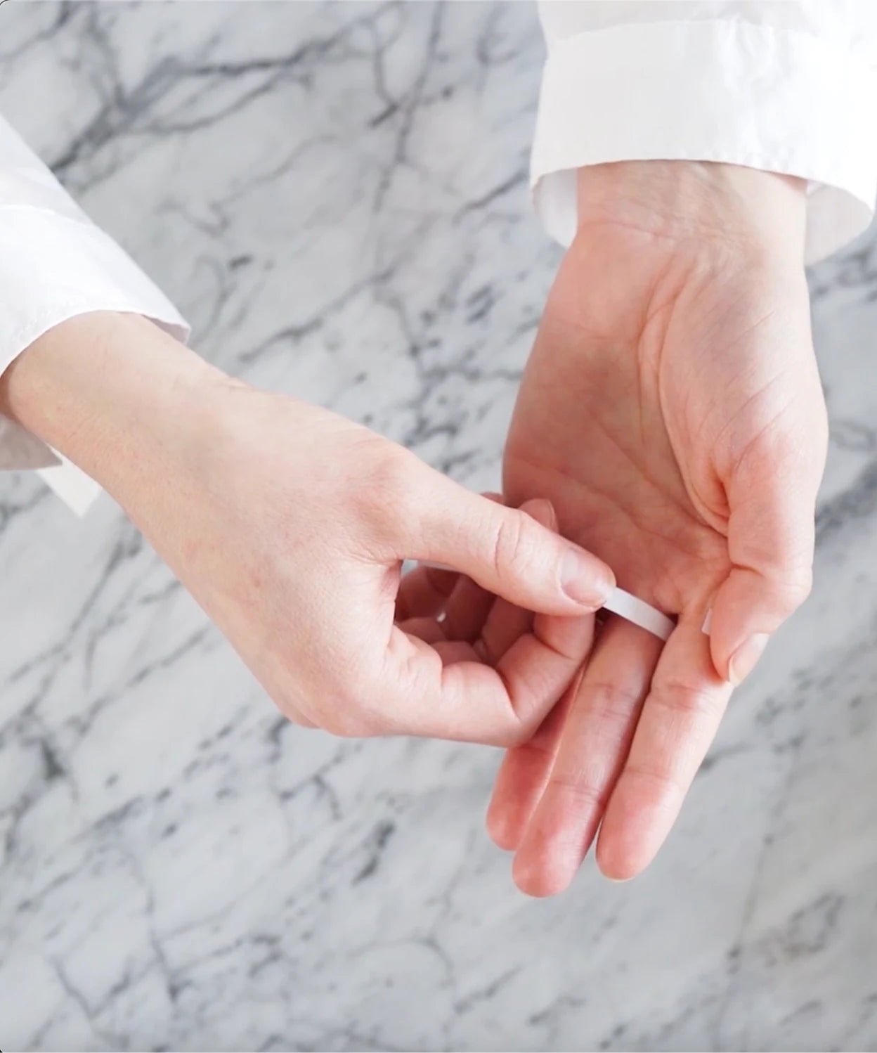 Close-up of a paper strip around a finger, showing the correct position for measuring ring size.