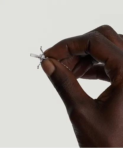 Hand holding an open tennis necklace clasp with safety arms, showing the clasp position before fastening.